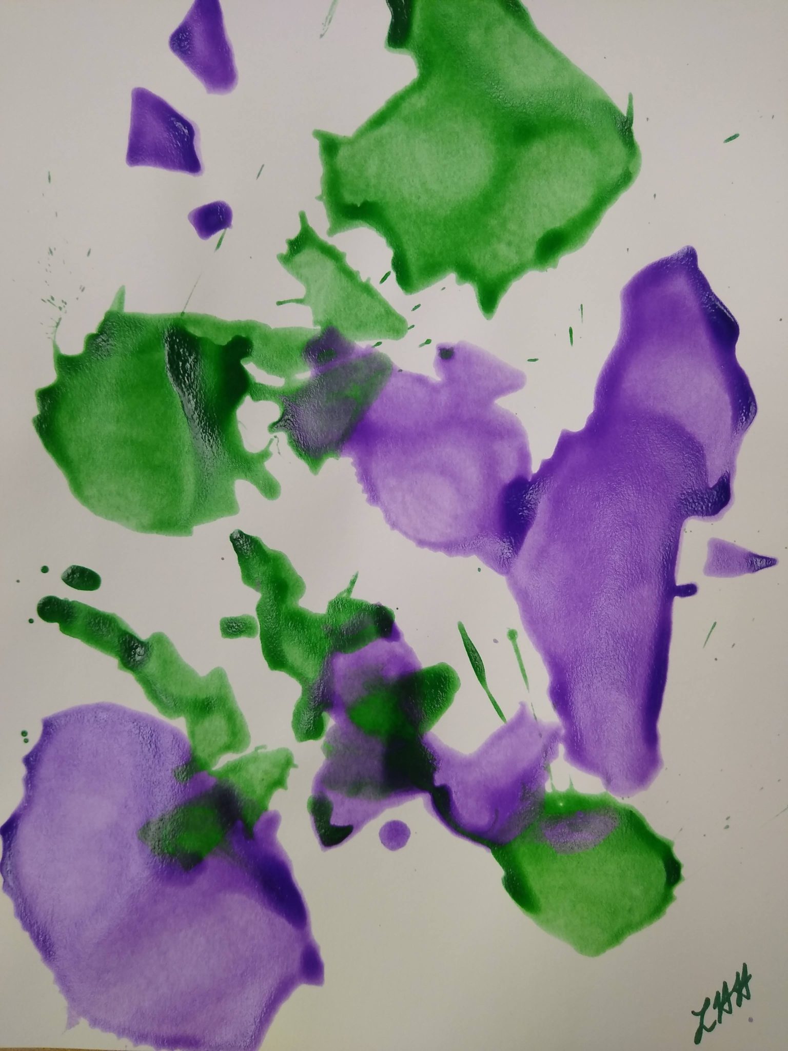 Looking down at a straw pointed at purple and green paint splotches on paper.