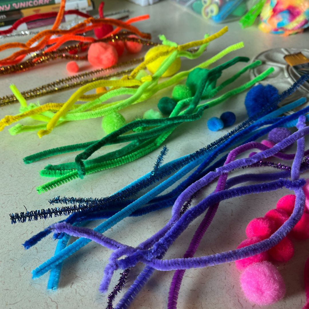 several different colored yarns and pom poms on a table