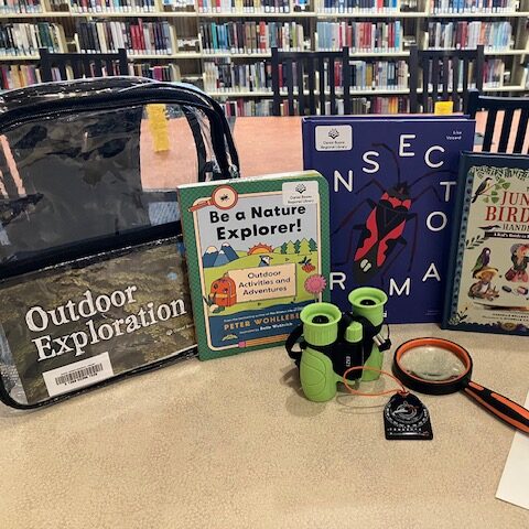 Display of contents of Outdoor Exploration Kit including backpack, books, binoculars, magnifying glass and compass