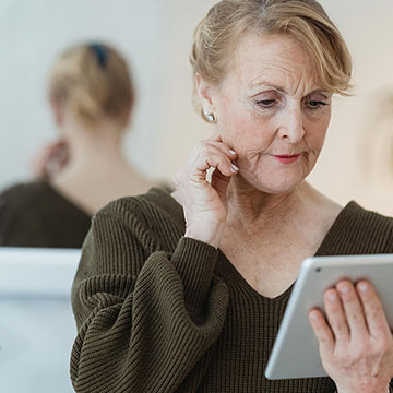 Lady with her attention focused on a tablet, looking thoughtful.