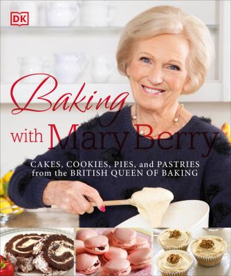 Mary Berry is standing at a counter, smiling and beating batter. Baked goods in front of her. 