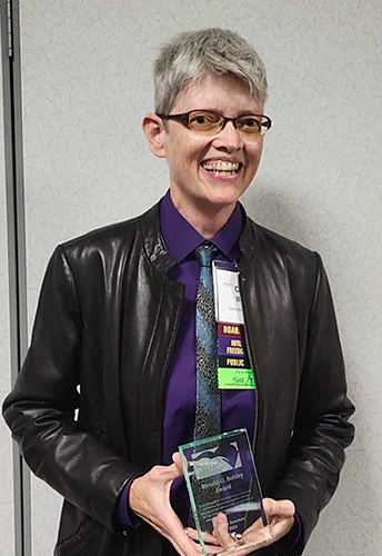 DBRL Librarian Otter Bowman holds their MLA award